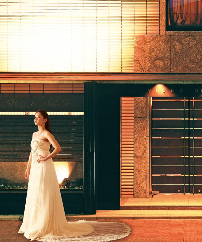 岡崎庵のエントランス前にウェディングドレス姿で立つ女性
